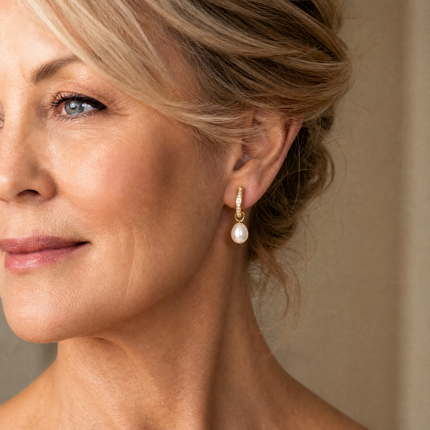 Close-up of a woman wearing pearl earrings with a neutral background